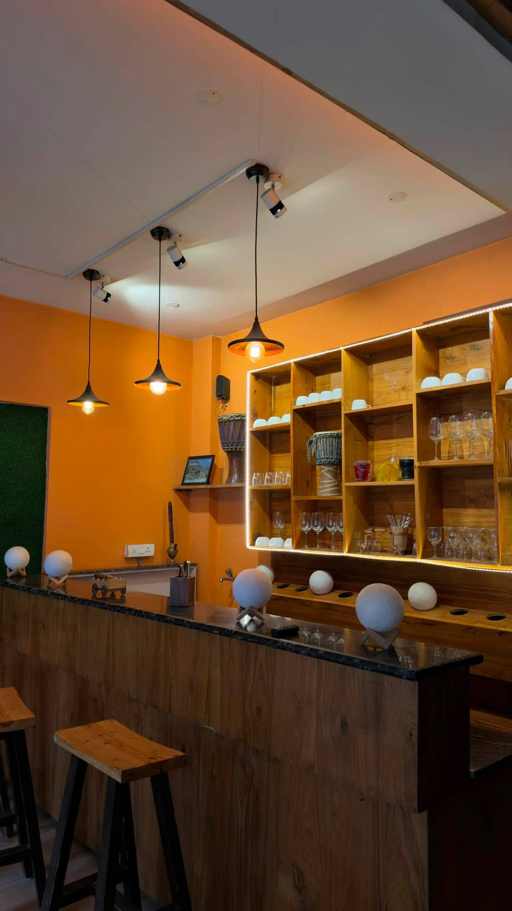 Wooden café bar with amber pendant lights and a backlit glass shelf