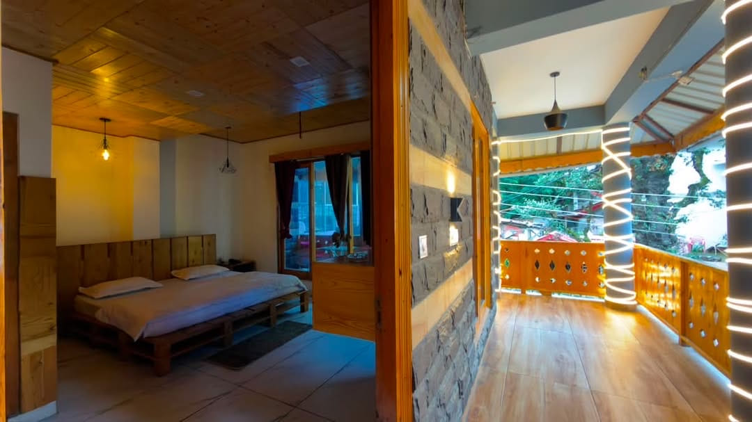Wooden hotel room beside a lit corridor opening to a mountain balcony