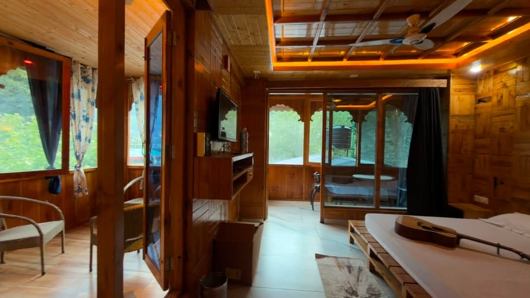 Timber hotel room with a guitar on the bed and doors open to a balcony